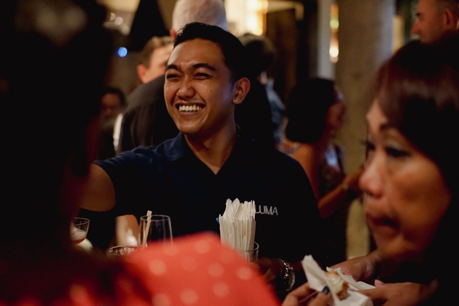 A member of Luma's floor team laughing while serving guests at the bar